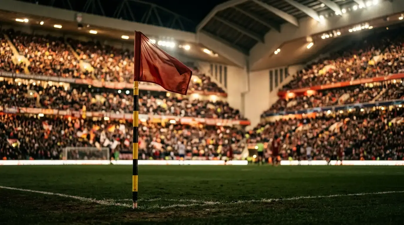 A close-up of a corner flag against a blurred backdrop of a floodlit indoor stadium under warm light