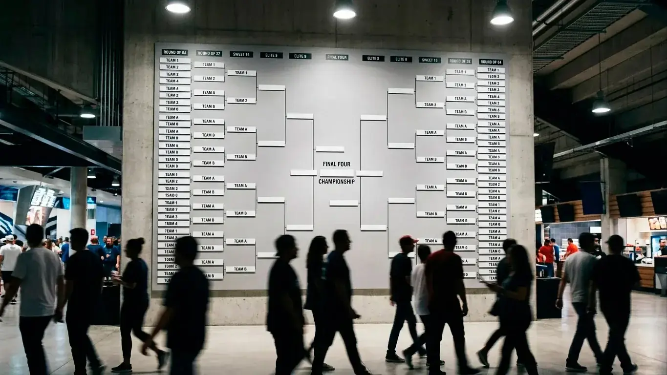 A tournament bracket wall in a stadium concourse, blurred fans passing beneath it